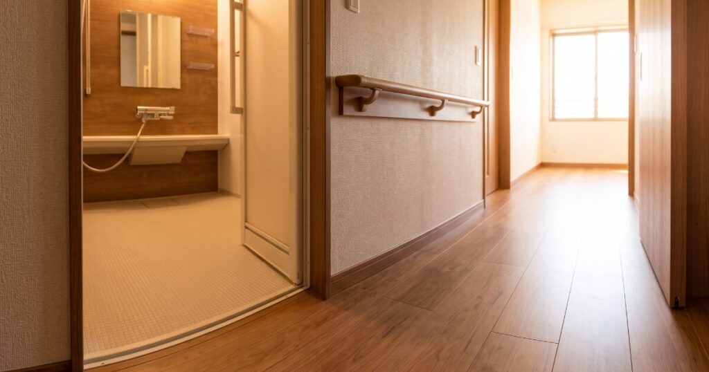 高齢者向け住宅のバリアフリーな室内環境。段差のない床と手すりが設置された廊下。転倒リスクを軽減し、ヒートショック現象を防ぐ設計。