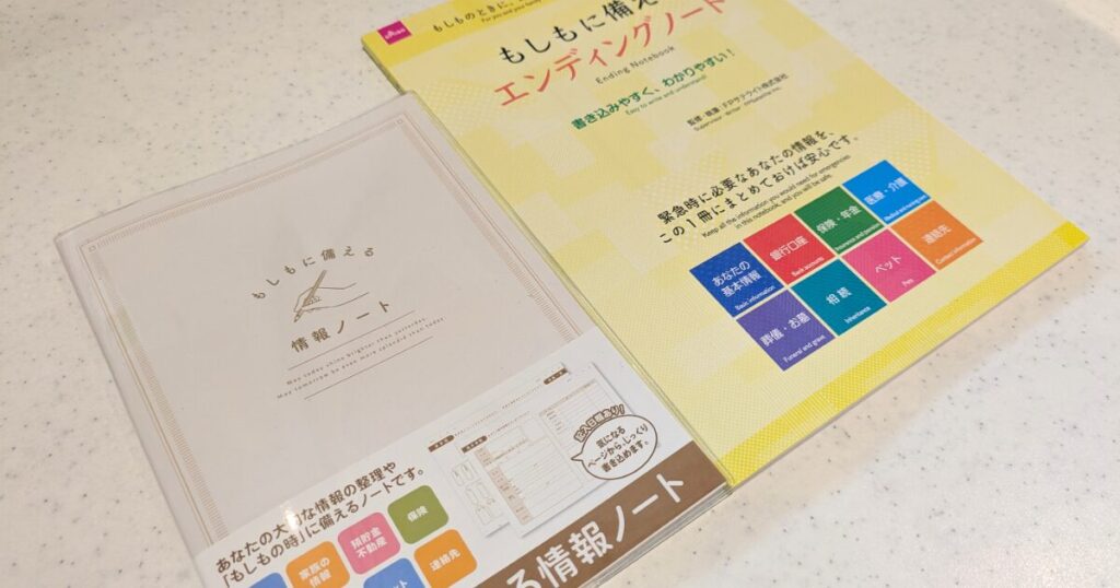 100円ショップのセリアが販売する薄型A5判の「もしもに備える情報ノート」（左）と、ダイソーが販売する黄色い表紙で本格的な「もしもに備えるエンディングノート」（右）を並べた実物比較写真。デザイン、サイズ、厚みの違いが一目でわかる。